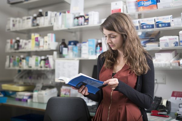 A Primary Care pharmacist consulting the BNF in her  pharmacy