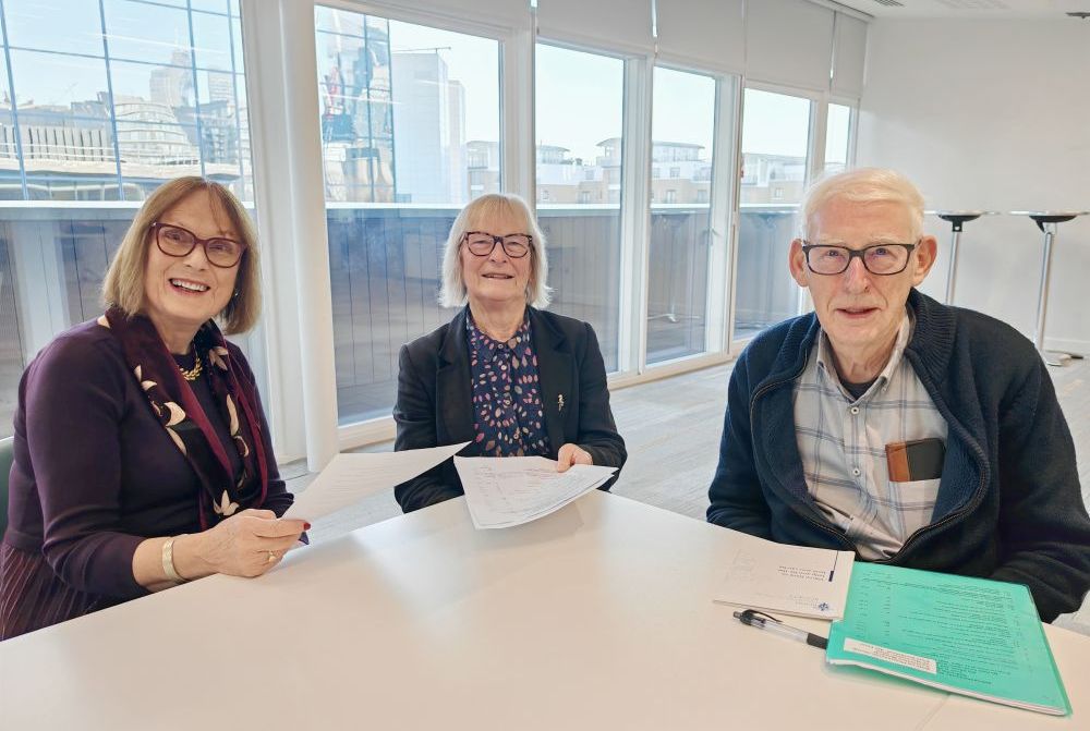 Three cheerful people sat round an office table