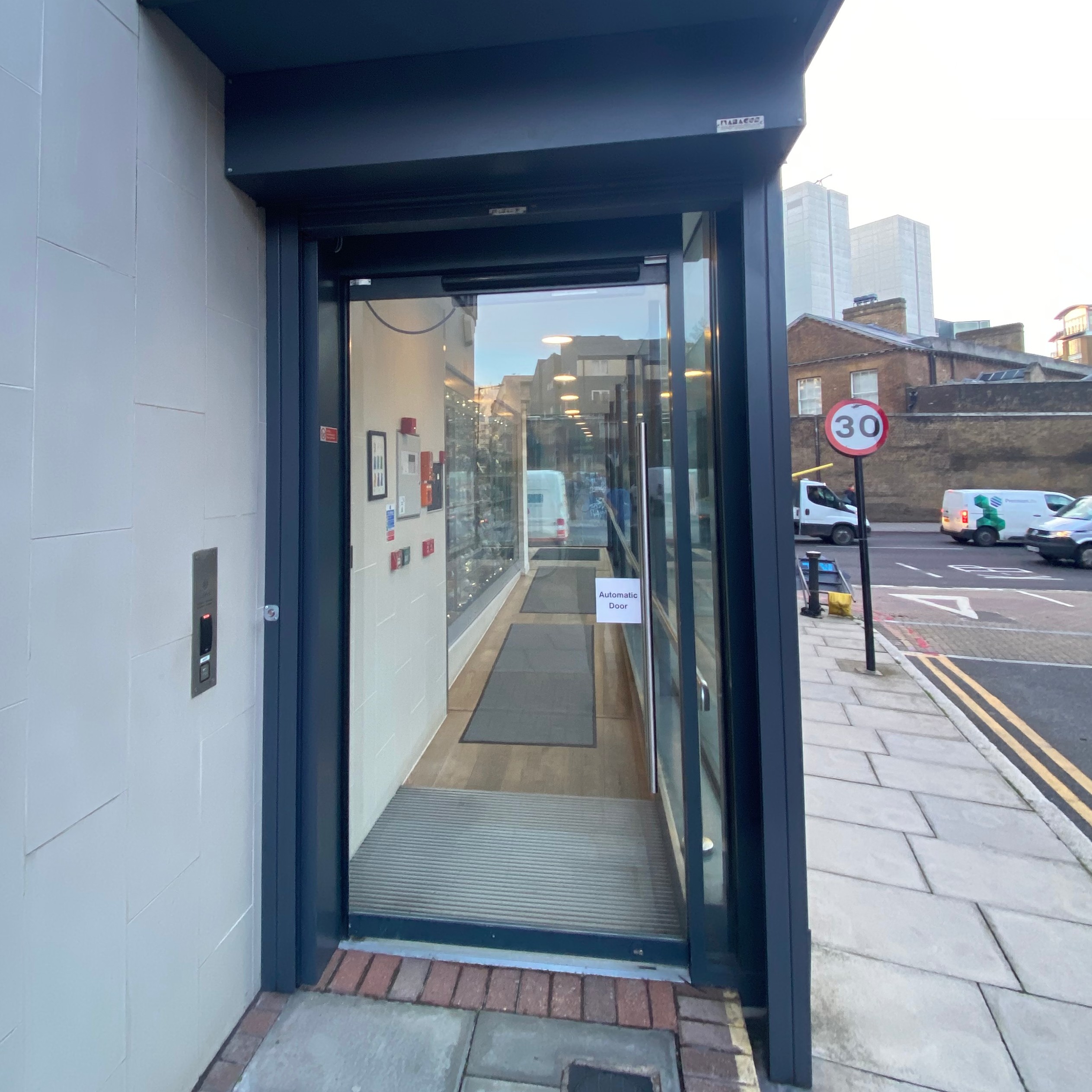 The glass front door of the RPS building, facing away from East Smithfield. The door is located on John Fisher Street. The doorbell is on the left hand side of the door.