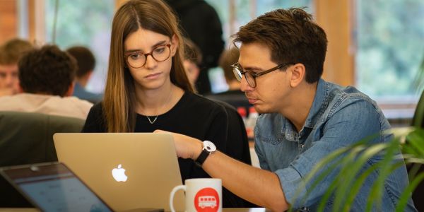 A man and a woman both looking at an open laptop